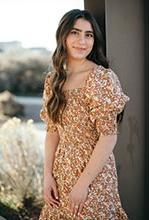 Bria Cohen leaning against pillar smiling at camera